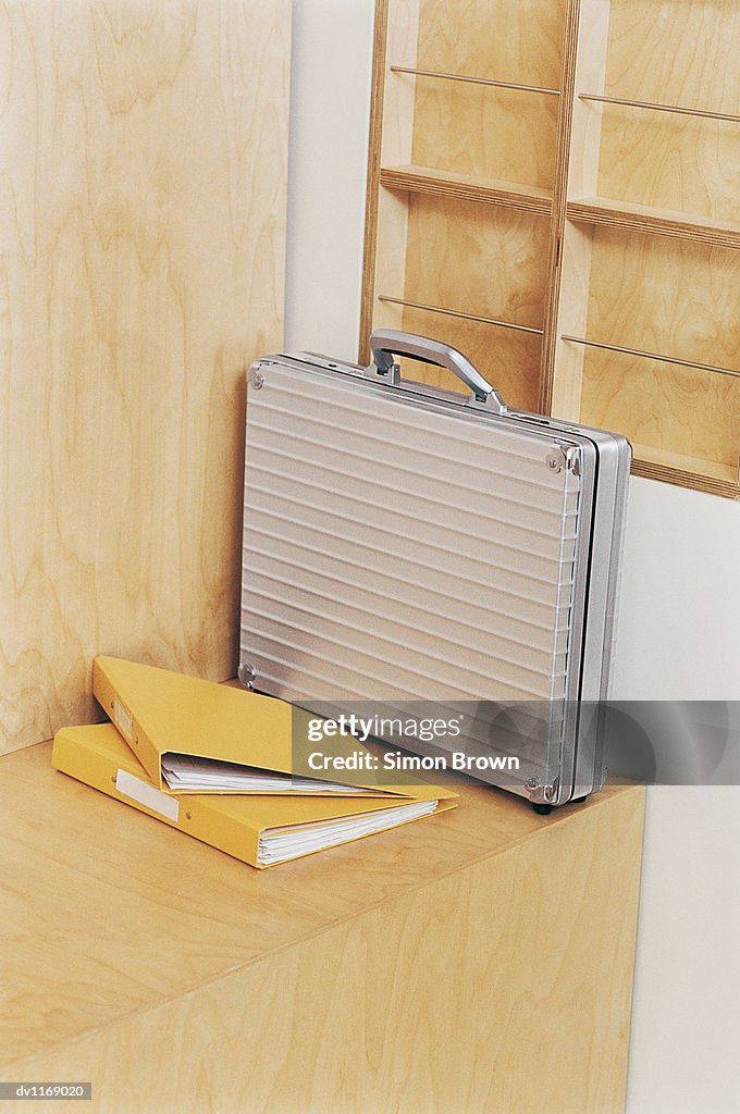 Briefcase and Two Ring Binders on a Wooden Bench in an Office