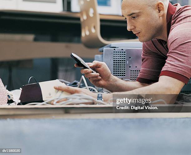 workman using a mobile phone at a business conference for help in installing machine parts - installation of memorial honors victims of ghost ship fire in oakland stockfoto's en -beelden