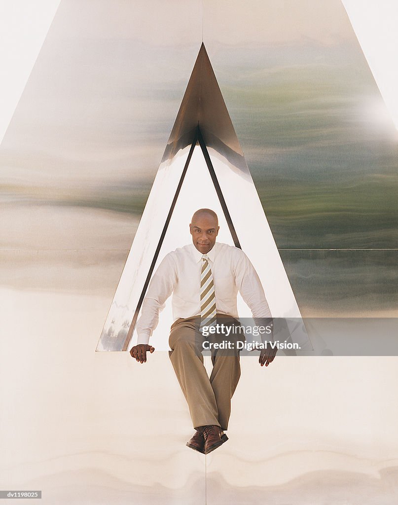 Businessman Sitting in the Centre of a Triangular Sculpture