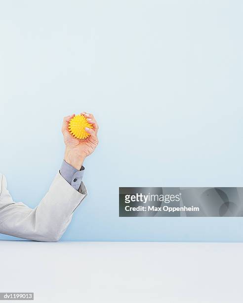 businessman's arm gripping a desk toy for stress - desk toy 個照片及圖片檔
