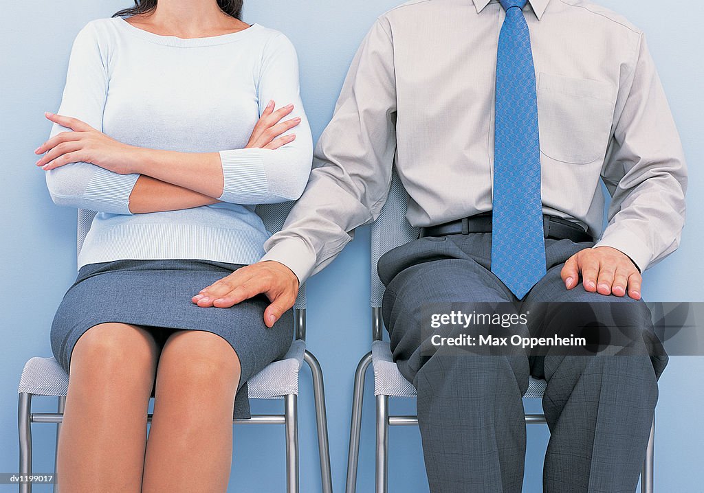 Mid Section View of a Businessman Touching the Thigh of a Businesswoman Sitting by Him