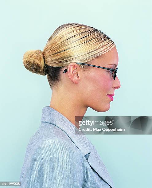 side view portrait of a young businesswoman with a hair bun and wearing spectacles - chignon bun photos et images de collection