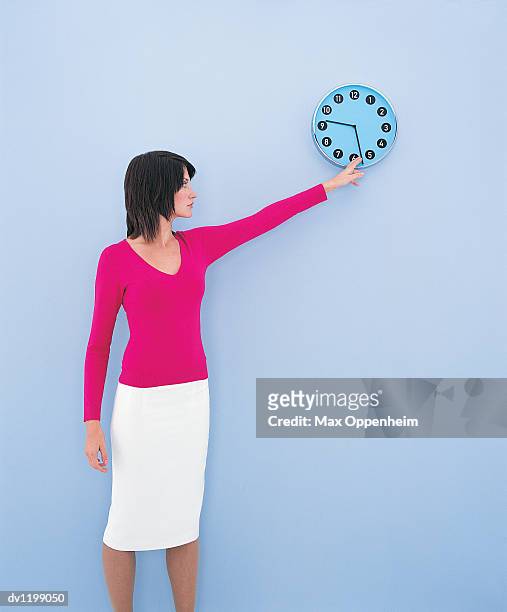 young businesswoman adjusting the minute hand on a wall clock - wanduhr stock-fotos und bilder