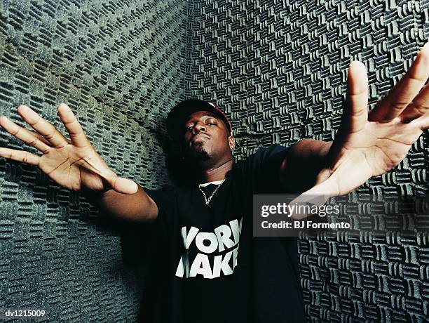 portrait of a male rapper standing in a recording studio with his arms outstretched - rap stock-fotos und bilder