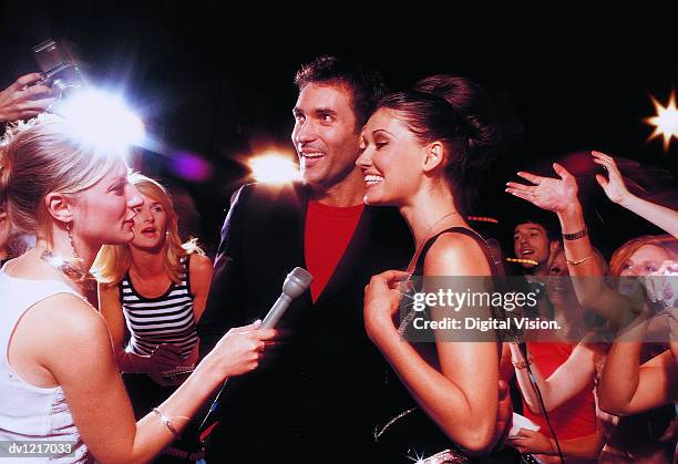 acting couple being interviewed by a tv reporter in front of a group of fans taking photographs - in front of camera stock pictures, royalty-free photos & images