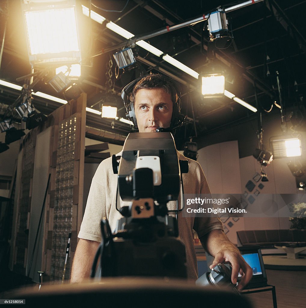 Cameraman Standing Behind a TV Camera in a TV Studio