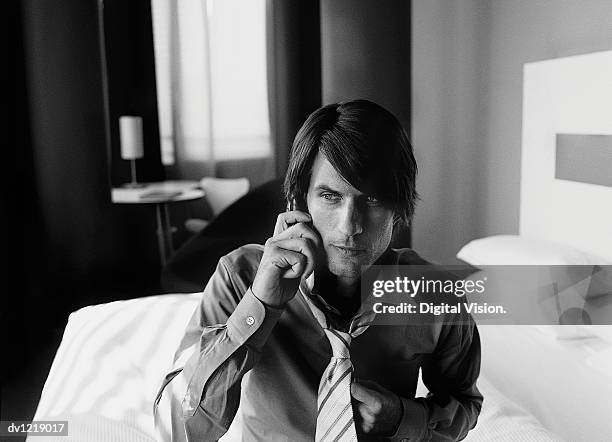 businessman sitting on the edge of a bed in a hotel room using his mobile phone - wonky fringe stock pictures, royalty-free photos & images