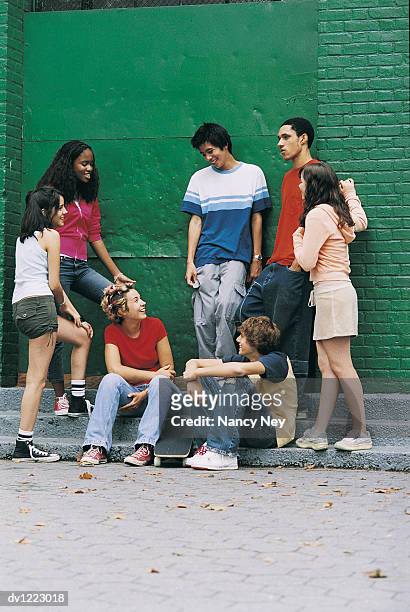 teenage boys and girls sitting and standing by a wall - nancy green stockfoto's en -beelden