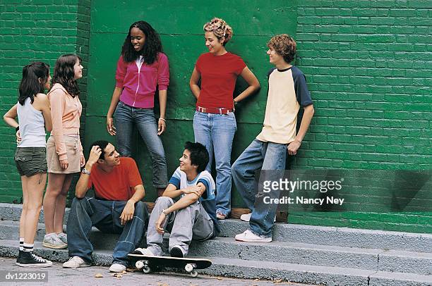 teenage boys and girls sitting and standing by a wall - nancy green fotografías e imágenes de stock