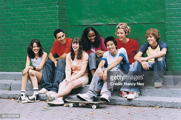 teenage boys and girls sitting by a wall - nancy green stockfoto's en -beelden