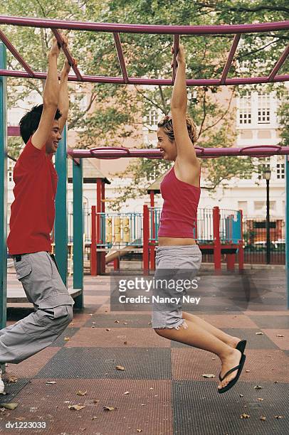 teenage couple hanging from a climbing frame face to face - climbing frame stockfoto's en -beelden