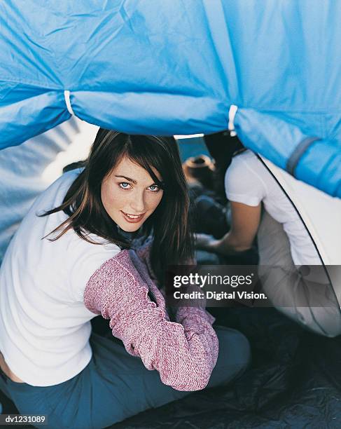 young woman sitting inside of a tent and putting on a polo neck jumper - polo neck stock-fotos und bilder