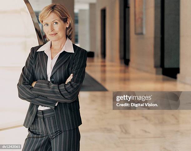 portrait of a mature businesswoman standing in a building lobby - riscas imagens e fotografias de stock