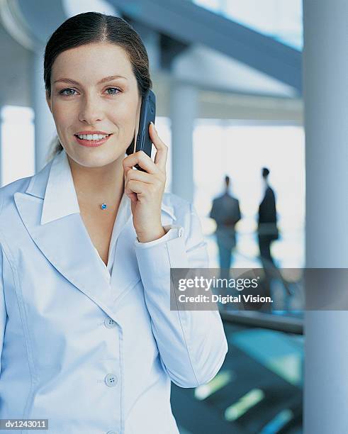 portrait of a businesswoman using a mobile phone in an office lobby - ojos grises fotografías e imágenes de stock