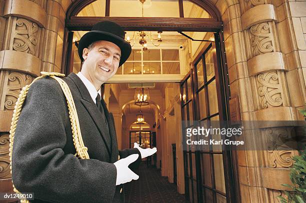 doorman gesturing towards a hotel entrance - door attendant imagens e fotografias de stock