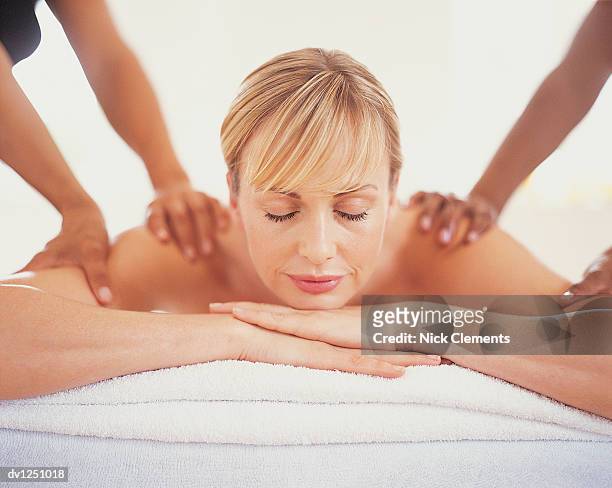 woman lying on treatment table with eyes closed having a shoulder massage - massage table no people stock pictures, royalty-free photos & images