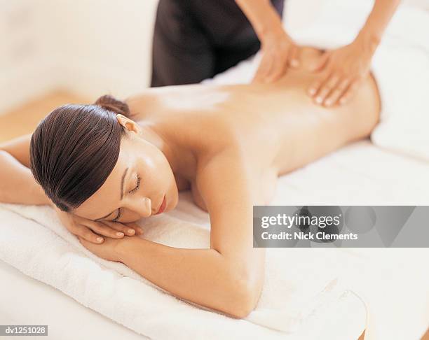 woman having a back massage as she lies on a treatment table - massage table no people stock pictures, royalty-free photos & images