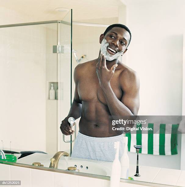 young man applying shaving foam on his face - man shaving foam stock pictures, royalty-free photos & images