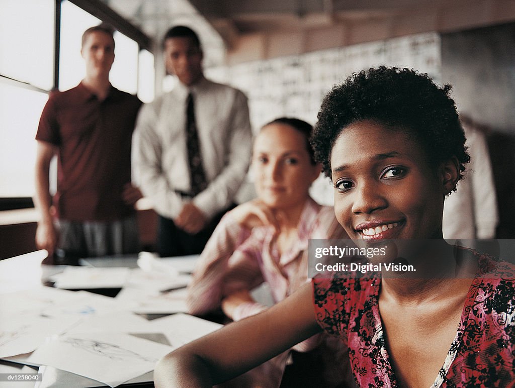 Portrait of a Fashion Designer Sitting in Front of Three of Her Colleagues at a Desk