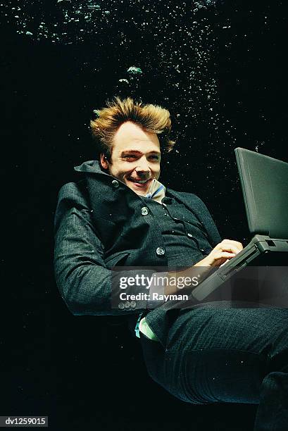 businessman using a laptop underwater - crazy man computer stock-fotos und bilder