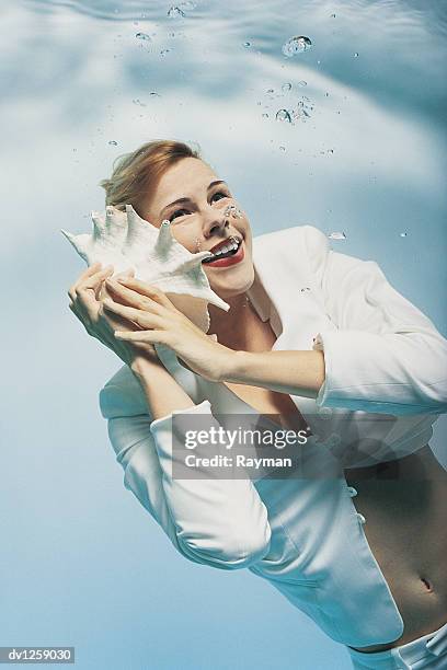 businesswoman underwater holding a seashell pretending it's a phone - business woman schild stockfoto's en -beelden