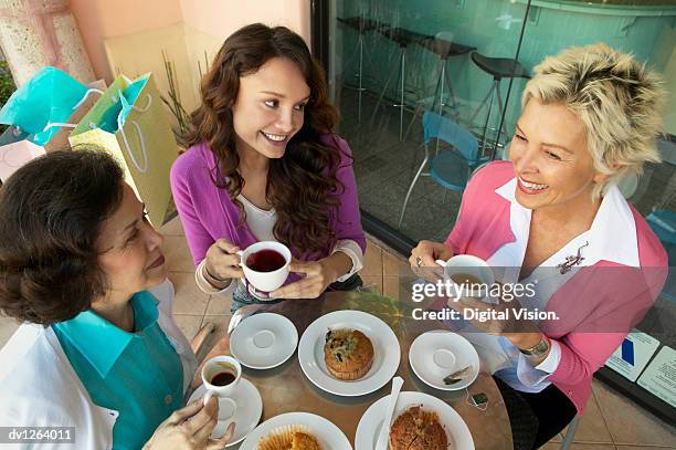 three women sit at a table on a patio having a coffee break and a snack - kaffeeklatsch stock-fotos und bilder