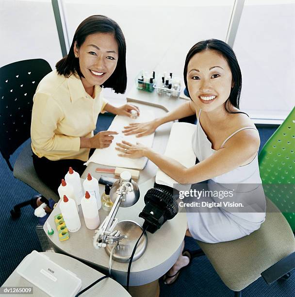 portrait of a woman in a beauty salon having a nail manicure from a beautician - beauty salon foto e immagini stock