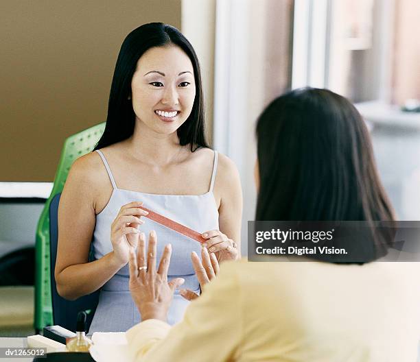 woman in a beauty salon having a nail manicure from a beautician - beauty salon foto e immagini stock