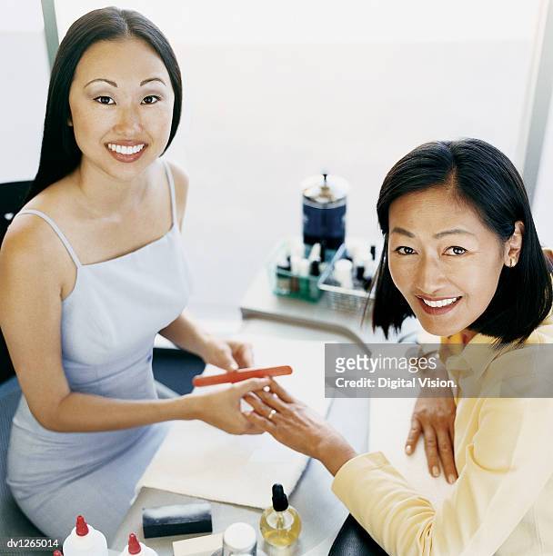 portrait of a woman in a beauty salon having a nail manicure from a beautician - beauty salon foto e immagini stock
