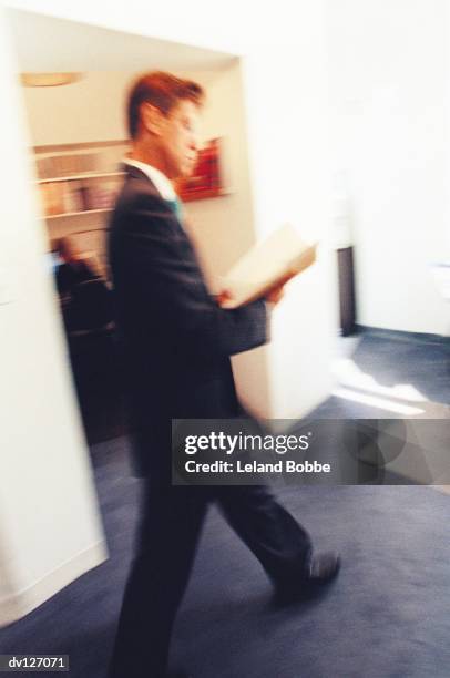 businessman in office, looking over papers - leland bobbe foto e immagini stock