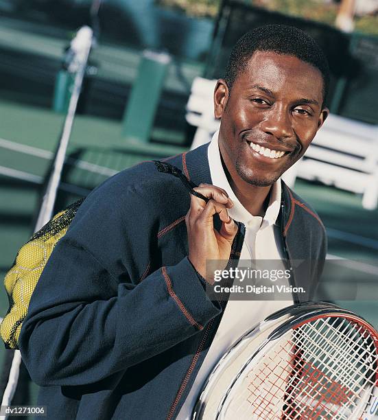 portrait of a young man on a tennis court holding tennis balls and a racket - tennis court stock pictures, royalty-free photos & images