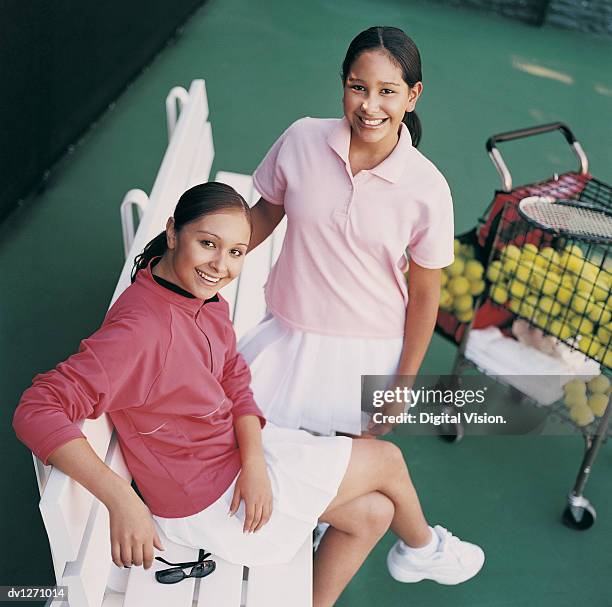 two teenage girls sitting on a bench on a tennis court - tennis court stock pictures, royalty-free photos & images