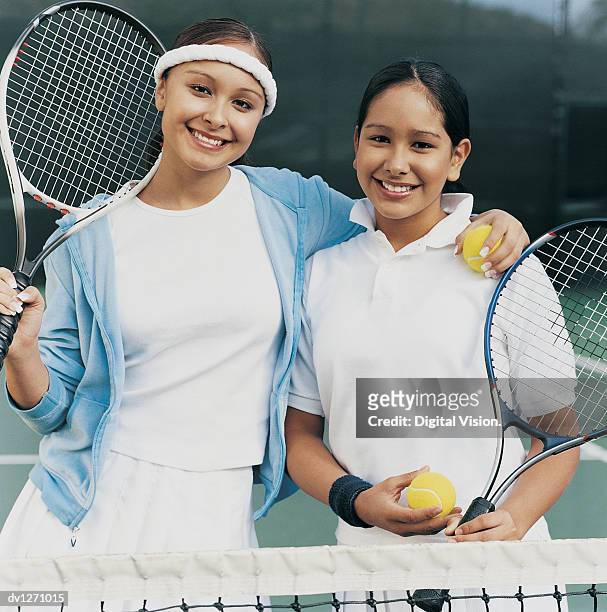 portrait of two teenage girls standing side by side on a tennis court - tennis court stock pictures, royalty-free photos & images