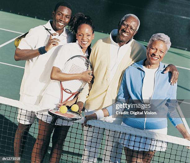 portrait of a family on a tennis court standing behind a tennis net - tennis court stock pictures, royalty-free photos & images