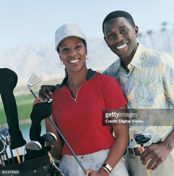 portrait of a couple standing holding golf clubs - top golf stock pictures, royalty-free photos & images