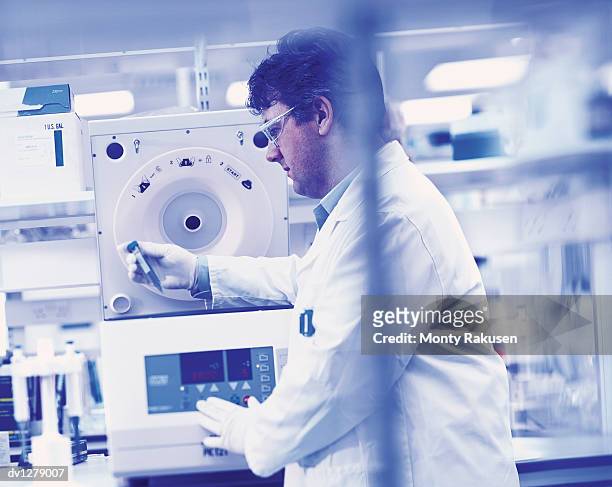 laboratory technician holding a medical sample and standing by a dna analysis machine - medical sample stock-fotos und bilder