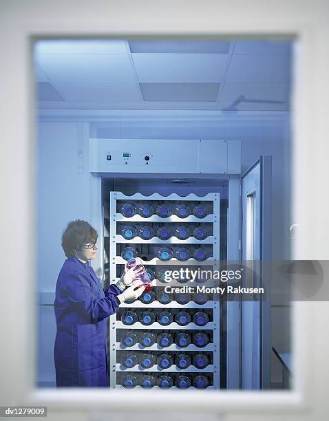 technician standing by the open door of a laboratory fridge and holding a genetic medical sample - medical sample stock-fotos und bilder