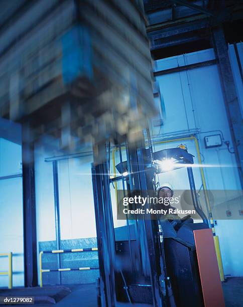 man lifting a payload on a fork lift truck, immingham port warehouse, uk - immingham stock pictures, royalty-free photos & images