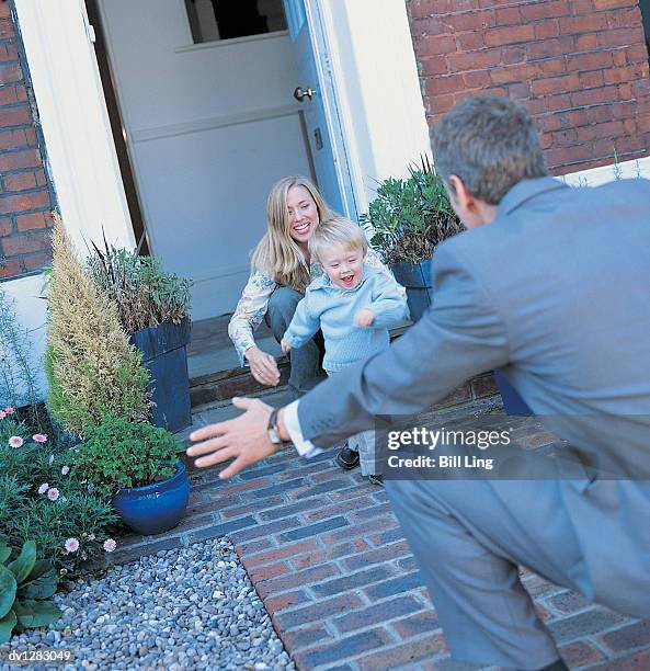 businessman greeting a mother and son on a path in his front yard - yard stockfoto's en -beelden