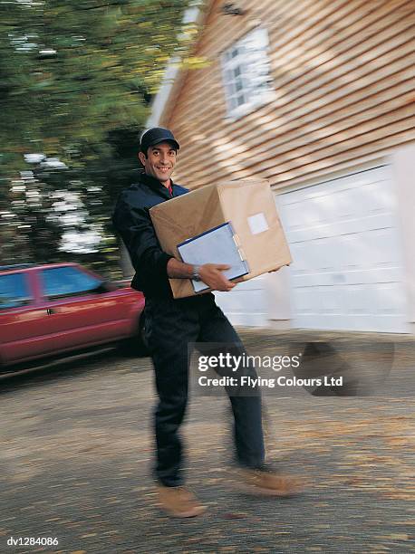 portrait of a delivery man holding a parcel walking up a driveway to a house - reliance industries ltd stock pictures, royalty-free photos & images