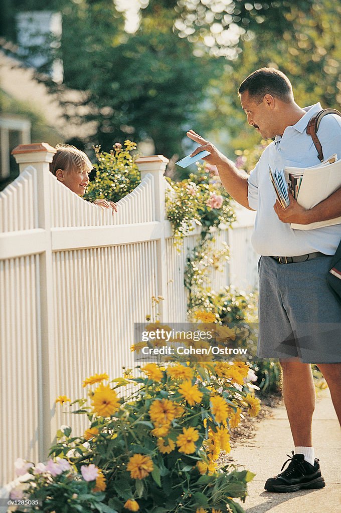 Postman Giving a Girl Her Mail Standing By a Picket Fence in Summer