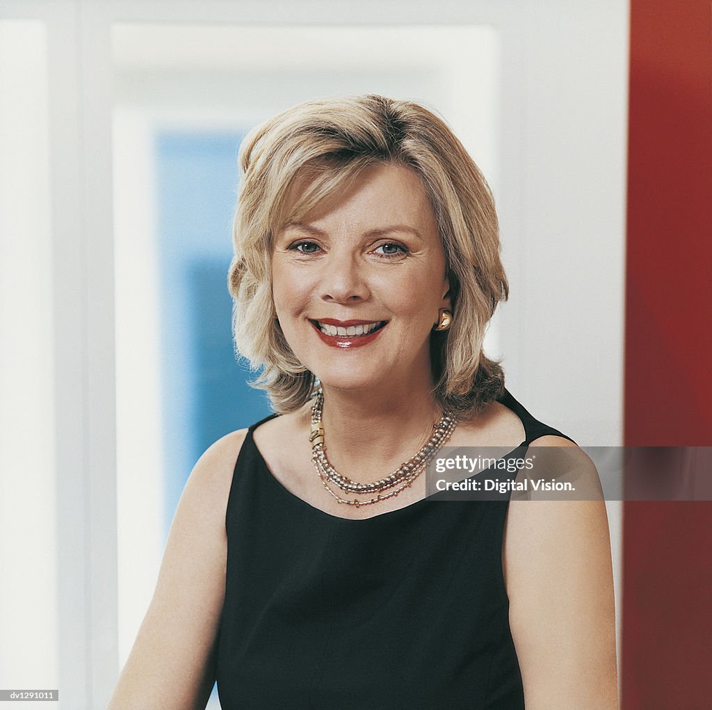 Portrait of a Blonde Businesswoman Sitting Smiling at Camera in Casual Evening Wear