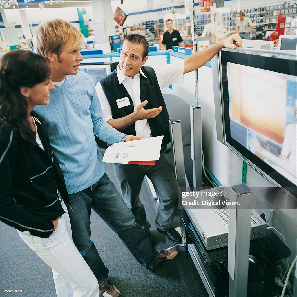 Young Couple Being Helped in a Department Store By a Shop Assistant to Buy a Plasma Screen