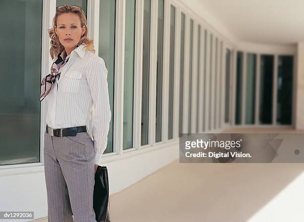 portrait of a confident businesswoman standing holding a handbag - fensterfront stock-fotos und bilder