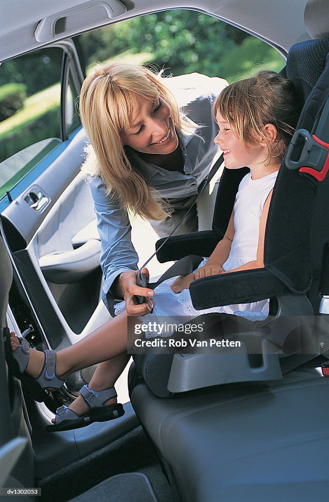 Mother Fastening Seatbelt Over Daughter in Car Seat