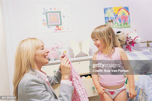 mother helping her daughter to get dressed - get stock pictures, royalty-free photos & images