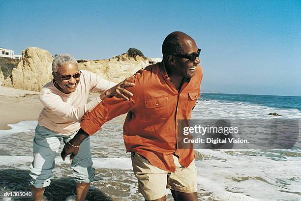 elderly couple messing about at waters edge - senioren spazieren sommer stock-fotos und bilder