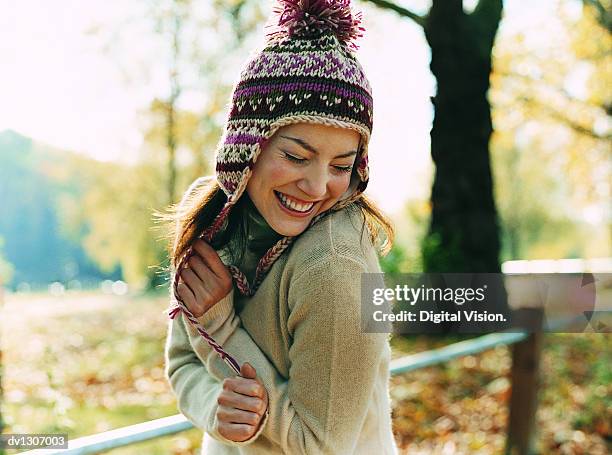 portrait of a young woman wearing a bobble hat smiling with her arms in front and her eyes closed - cuello alto fotografías e imágenes de stock