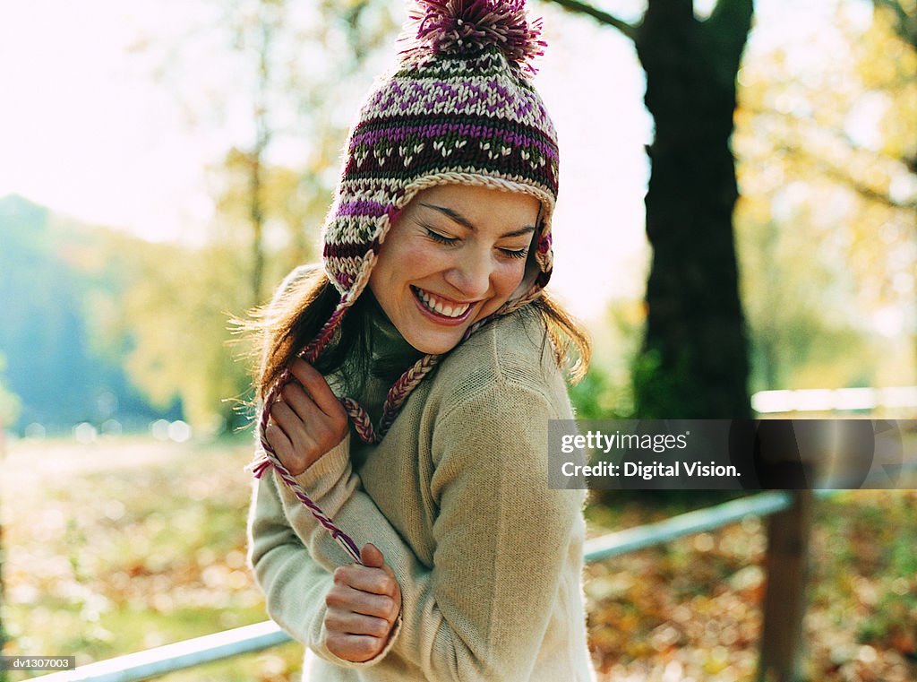 Portrait of a Young Woman Wearing a Bobble Hat Smiling With Her Arms in Front and Her Eyes Closed