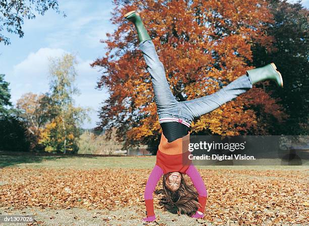 portrait of a young woman doing a cartwheel in a park - cartwheel stock pictures, royalty-free photos & images